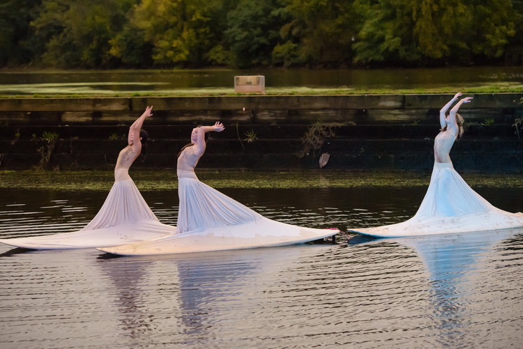 Performers in elegant dresses dancing on boats.